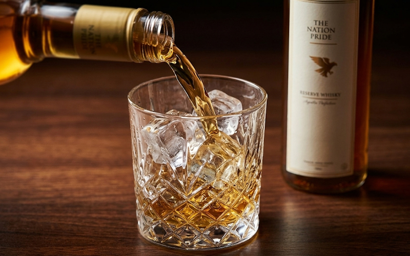 The Nation Pride whisky Indian best whisky with rich golden color in glass